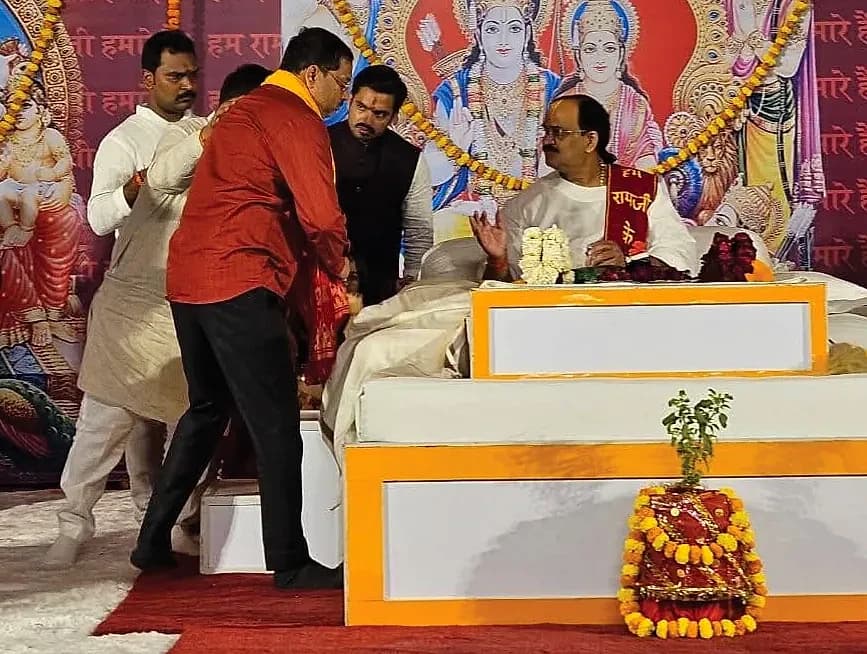 Vinod Kumar Upadhyay greeting a seated guest on the stage of a religious and cultural event